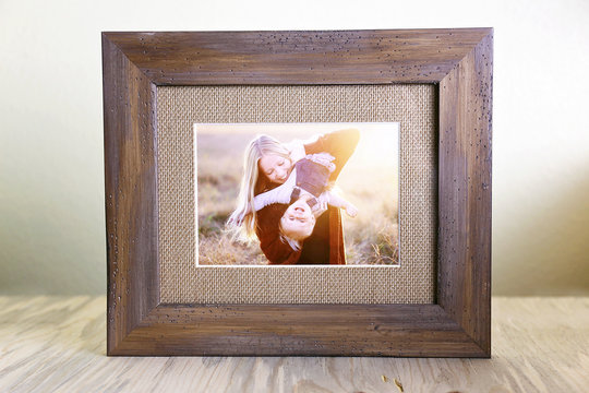 Rustic Wood Framed Portrait of a Mother and Her Baby Playing Outside at Sunset