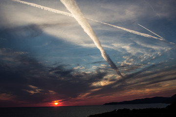 traces of airplane flying in the cloudy sky at sunset