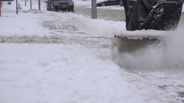 worker with snow blower clean snow from footpath on snowy street at winter. 4K