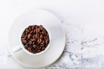 Coffee beans in white coffee cup brown white background