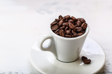 Coffee beans in white coffee cup brown white background