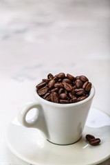 Coffee beans in white coffee cup brown white background