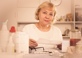 Mature woman with medicines and bills