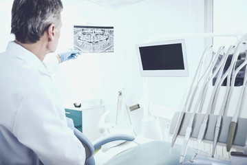 Portrait of a senior dentist analising x-ray in dental clinic