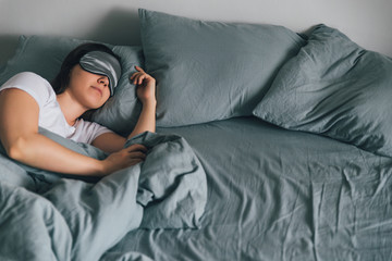 woman sleep in eye patch in grey bed. copy space - obrazy, fototapety, plakaty