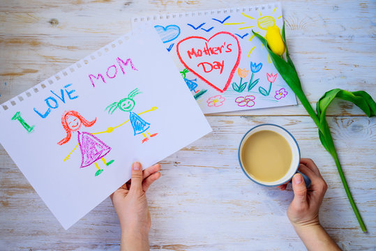 mother look on kid picture with mother day congratulation while drink coffee. overhead view