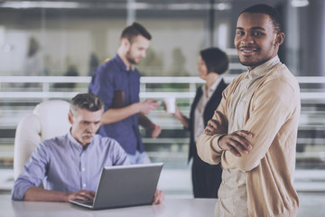 Young african businessman standing with crossed hands business people on background