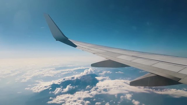 Plane wing view of a plane flying over the clouds