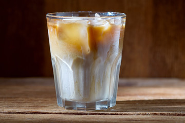 Coffee with ice and cream in a glass on a wooden background.
