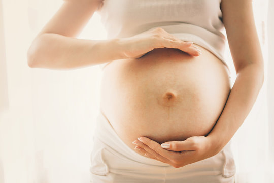 Pregnant woman isolated on  background. Holding her belly