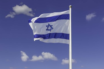 Fototapeta na wymiar Israel flag flapping in the wind isolated against the blue sky. The flag is on a pole and flapping to the left. there are white clouds in the sky