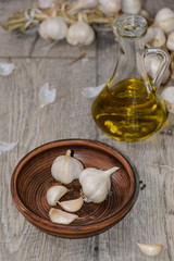 Garlic in a clay dish with olive oil on a table