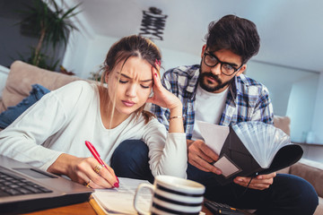Woman and man doing paperwork together, paying taxes online on notebook pc