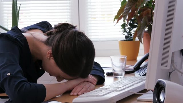 A woman looks angry at the computer screen and lowers her head on the keyboard