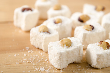 Fototapeta na wymiar Eastern sweets, Turkish delight with coconut flakes, hazelnuts on wooden table