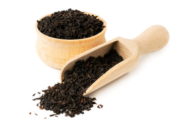 Black tea leaves in wooden plate and spoon on a white
