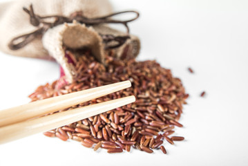 Wild red rice with sticks on white background