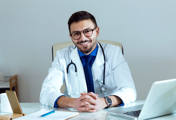 Confident male doctor smiling and looking at camera in the office.