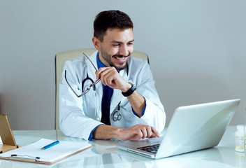 Confident male doctor working with his laptop in the office.