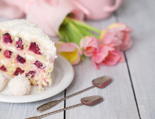 A cake with cherries and pink tulips on white wooden table