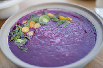 Close up of a purple beet soup topped with dill and tomotoes