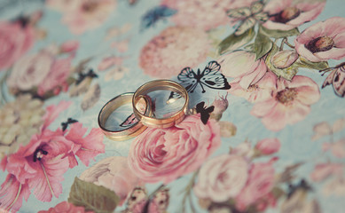 Two wedding rings of white gold on a blue butterflies background
