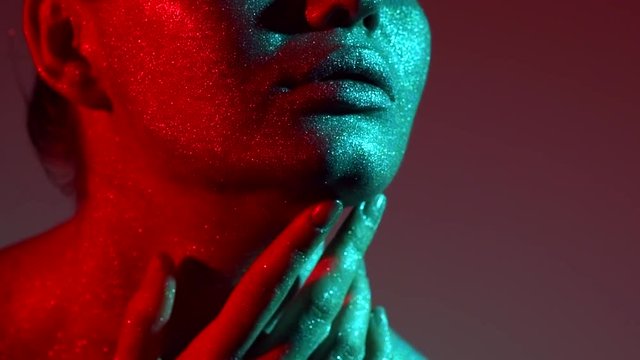 Fashion model woman in colorful bright sparkles and neon lights posing in studio, portrait of beautiful sexy girl. Art design colorful vivid makeup. Slow motion 4K UHD video footage. 3840X2160
