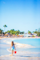 Fototapeta na wymiar Adorable little girl playing with beach toys on white tropial beach