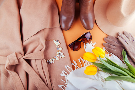 Spring female outfit with yellow tulips. Set of clothes, shoes and accessories on orange background
