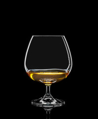 Cognac glass with drink on black