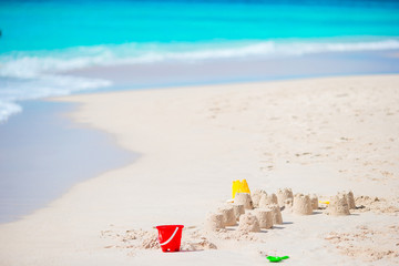 Fototapeta na wymiar Sandcastle at white tropical beach with plastic kids toys