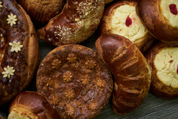 Traditional Russian Easter baked goods, kulichi, patties with cottage cheese, karavai and loaf cake with nuts on festive table background