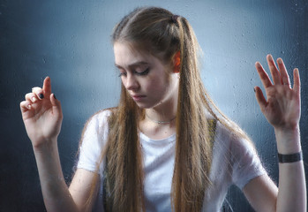 A beautiful, young girl is sad for a blind window