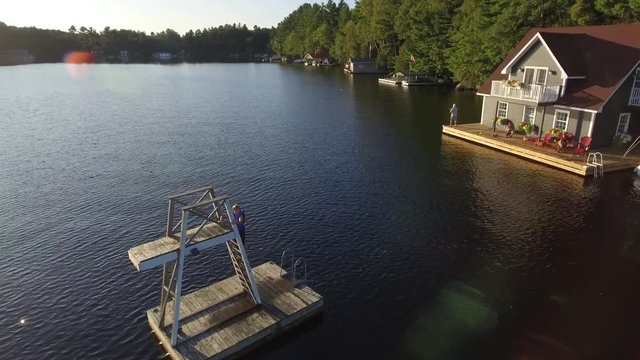 aerial kid climbs ladder of floating tower on lake