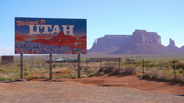 A sign welcomes visitors to Utah with Monument Valley background.