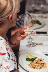 woman holds the glass of white wine and try how it smells