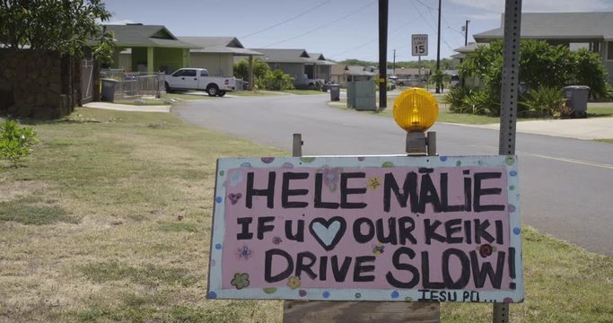 A sign in a Hawaiian neighborhood urges people to slow down and respect safety.