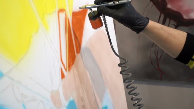 Artist draws a colorful painting with a paint sprayer. HD video