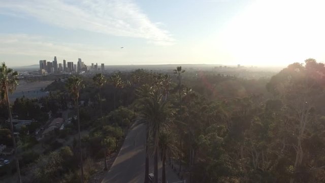 Amazing aerial drone clip of Los Angeles and sunlight behind park trees