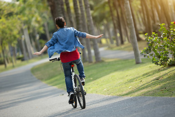Obraz premium happy woman cyclist riding bike in spring tropical park