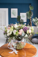 Sunny spring morning in living room. Beautiful luxury bouquet of mixed flowers in glass vase on wooden table. the work of the proffesional florist at a flower shop.