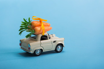 Toy car carrying easter carrots isolated on blue background