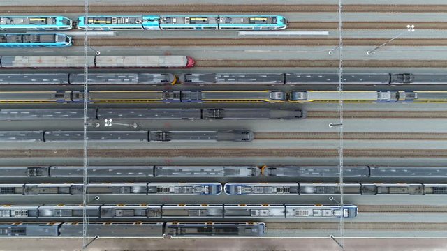 Aerial top down footage of railway transportation hub showing the different trains parked next to each other on the rails very smooth and right movement keeping the horizontal lines straight 4k