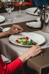 Woman eats salad with brie cheese, dandelions and strawberries.