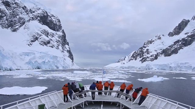 POV of ship's bow with tourists in the ice of Lemaire Channel in Antarctica. 