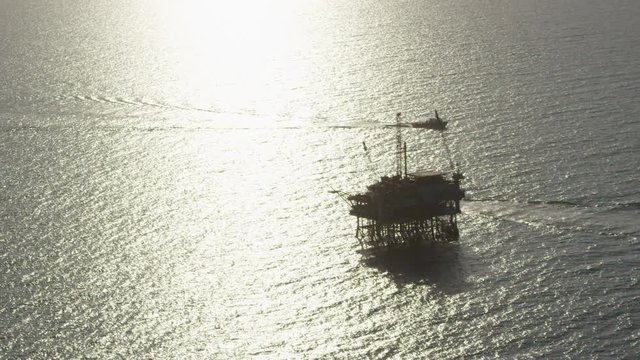 A beautiful aerial shot over a boat heading out to oil derricks and platforms in the Santa Barbara Channel, California.