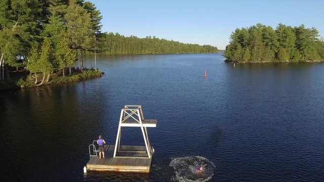 young girl jumps backwards from floating tower on lake ascend scenery reveal amazing aerial