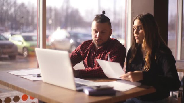 young freelancers man and woman sitting in a cafe and working for a laptop