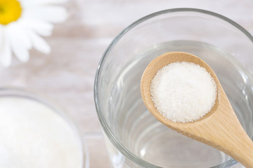 Collagen protein powder in the spoon. Glass of water