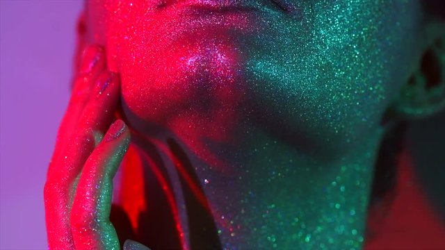 Fashion model woman in colorful bright sparkles and neon lights posing in studio, portrait of beautiful sexy girl. Art design colorful vivid makeup. Slow motion 4K UHD video footage. 3840X2160